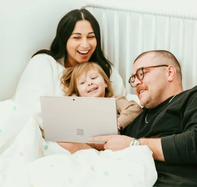 A cheerful family smiles for a photo, with a Microsoft Surface Pro 4 placed on a table in their outdoor setting
